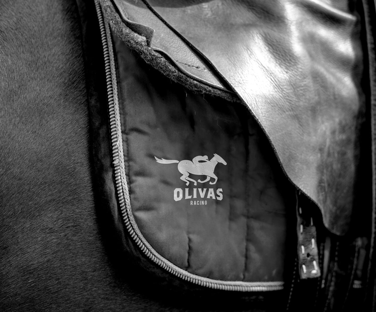 Close up shot of a horse saddle embroidered with the Olivas Racing logo